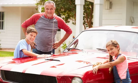 Grandfather and grandchildren with classic car